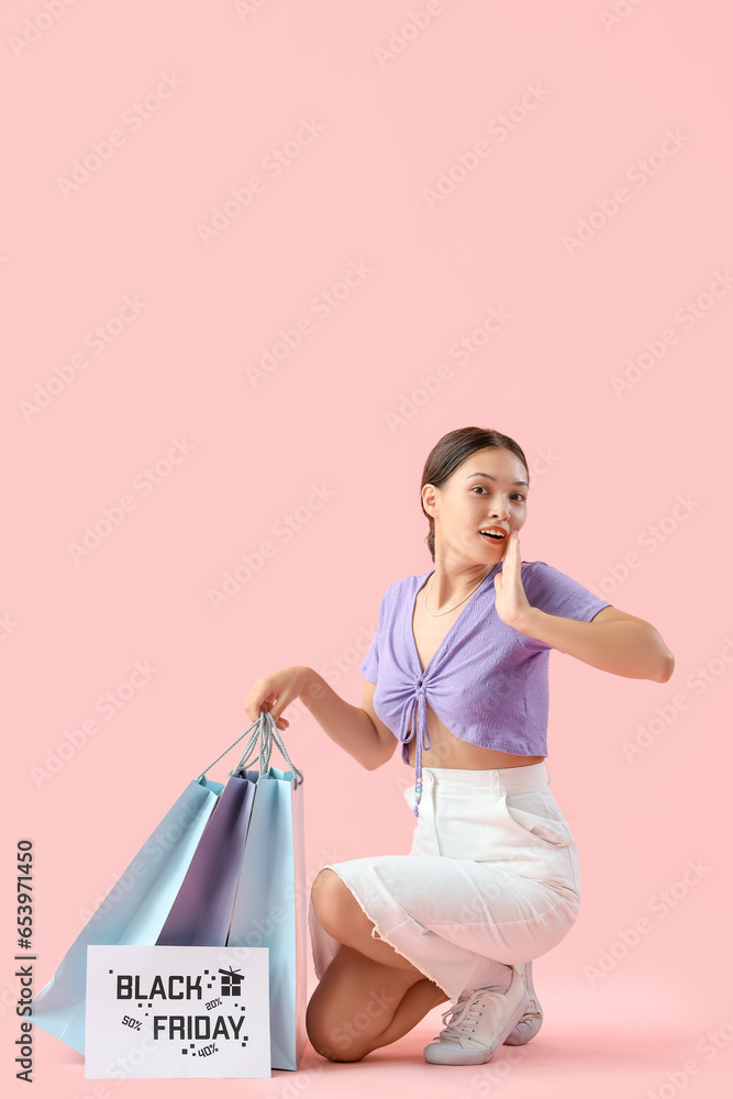 Surprised young Asian woman with shopping bags on pink background. Black Friday sale