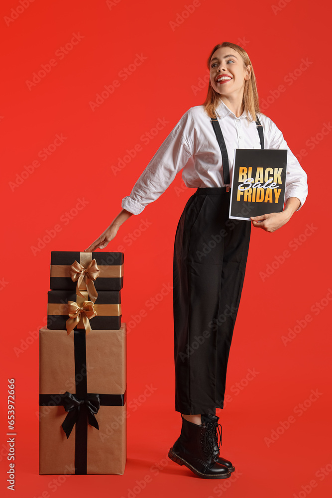 Young woman with card and gifts on red background. Black Friday sale