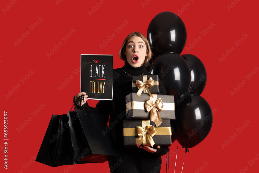 Shocked young woman with shopping bags, gifts and balloons on red background. Black Friday sale