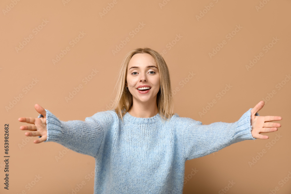 Young woman opening arms for hug on beige background