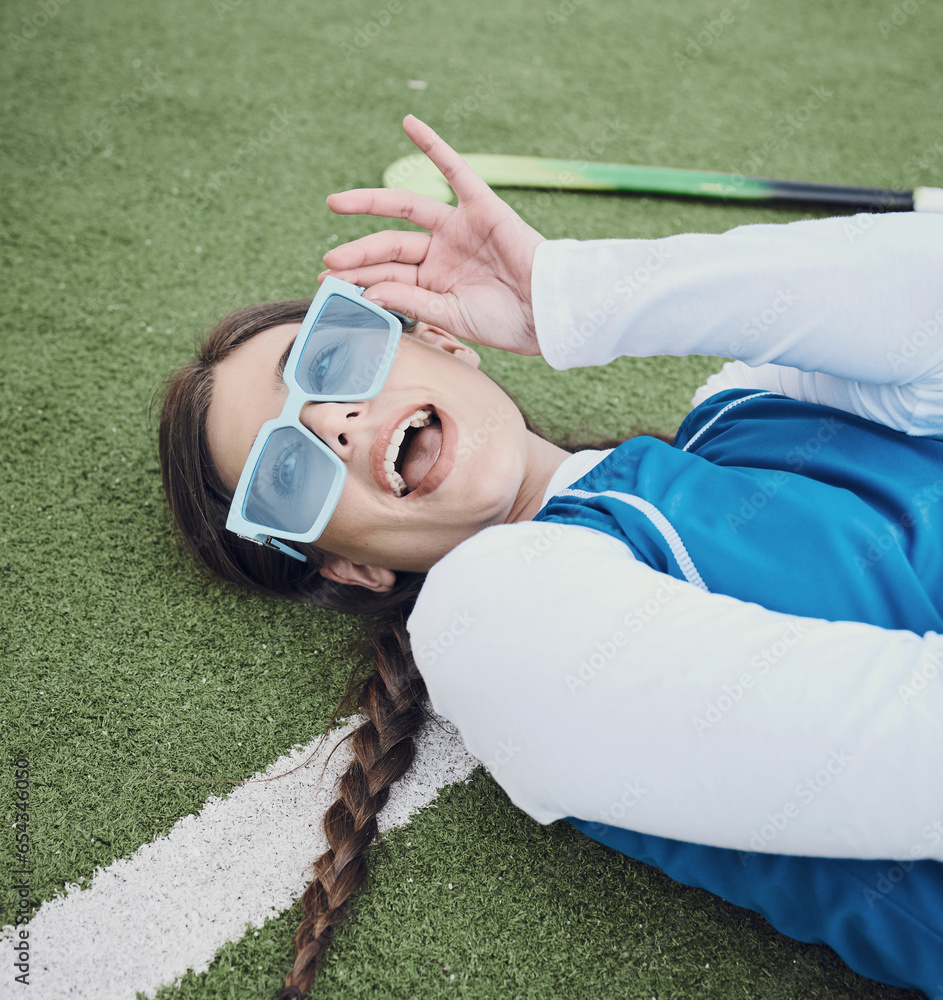 Woman, hockey and laying on field, break and closeup of sunglasses, pose and relax for practice, training and workout. Happy athlete, playful and excited for exercise, fashion and accessories for fun