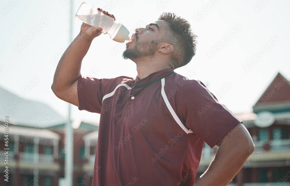 Football player, drink water and rest on sports field for training completion, workout and exercise outdoors. Fitness, workout and male athlete with liquid bottle for wellness, hydration or practice