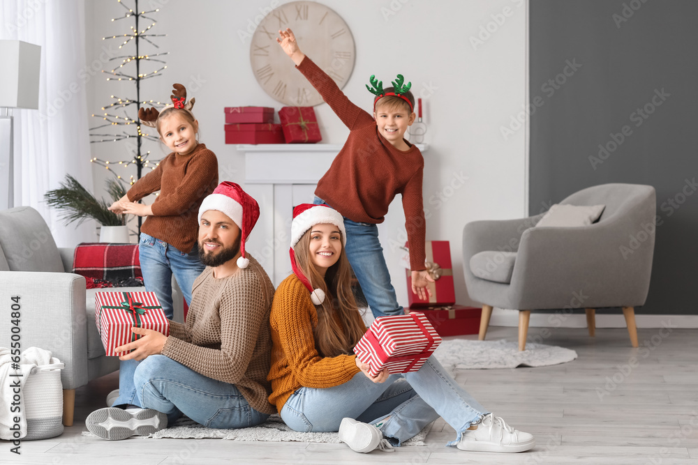 Happy parents and their little children with Christmas presents at home