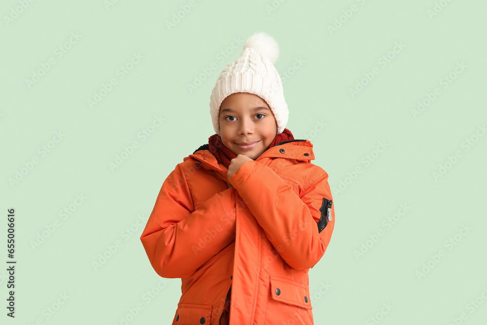 Cute African-American boy in warm winter clothes on light background