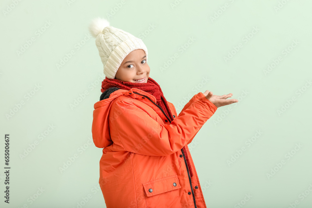 Cute African-American boy in warm winter clothes on light background