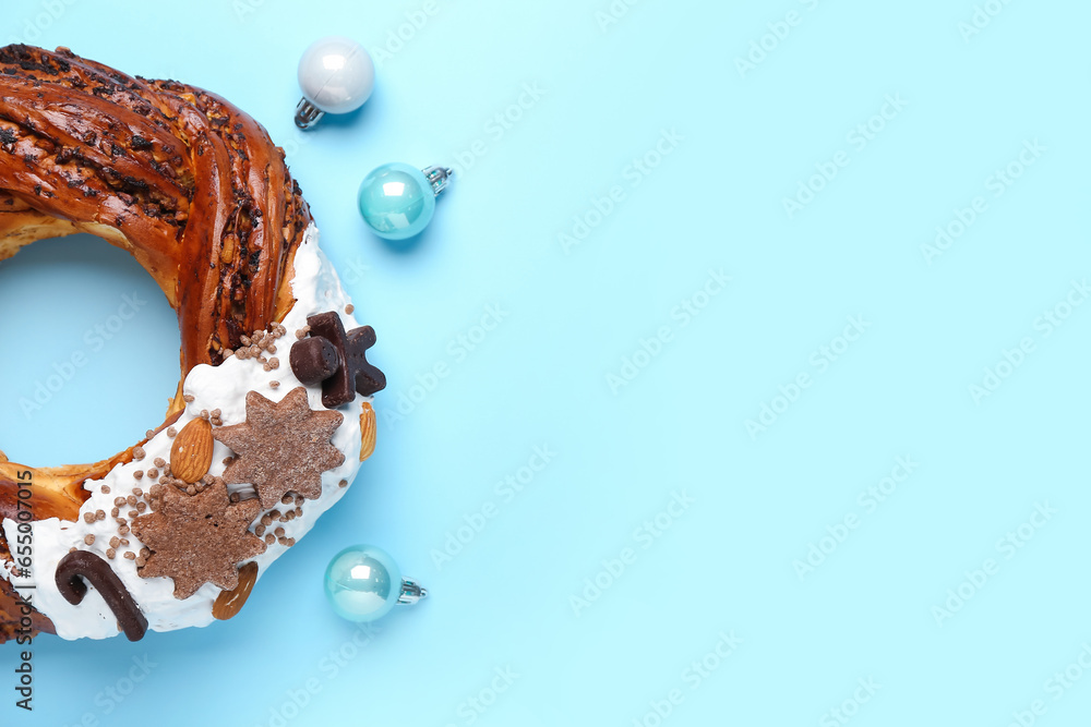 Tasty pastry wreath with Christmas balls on blue background