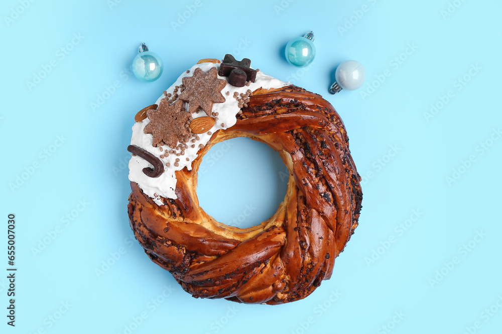 Tasty pastry wreath with Christmas balls on blue background