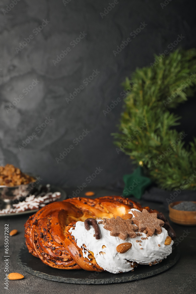 Board with delicious Christmas pastry wreath on dark background