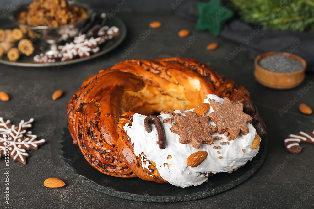 Board with delicious Christmas pastry wreath on dark background