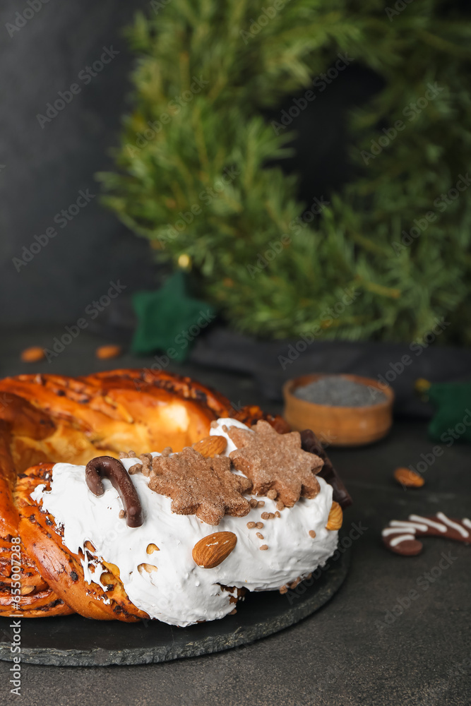 Board with delicious Christmas pastry wreath on dark background, closeup