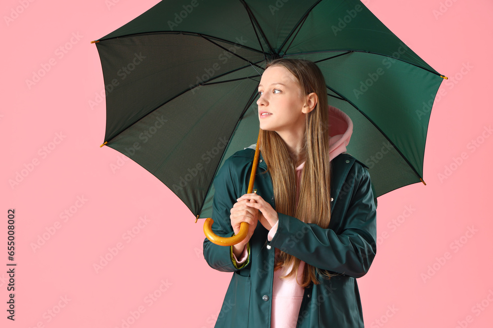 Teenage girl with green umbrella on pink background