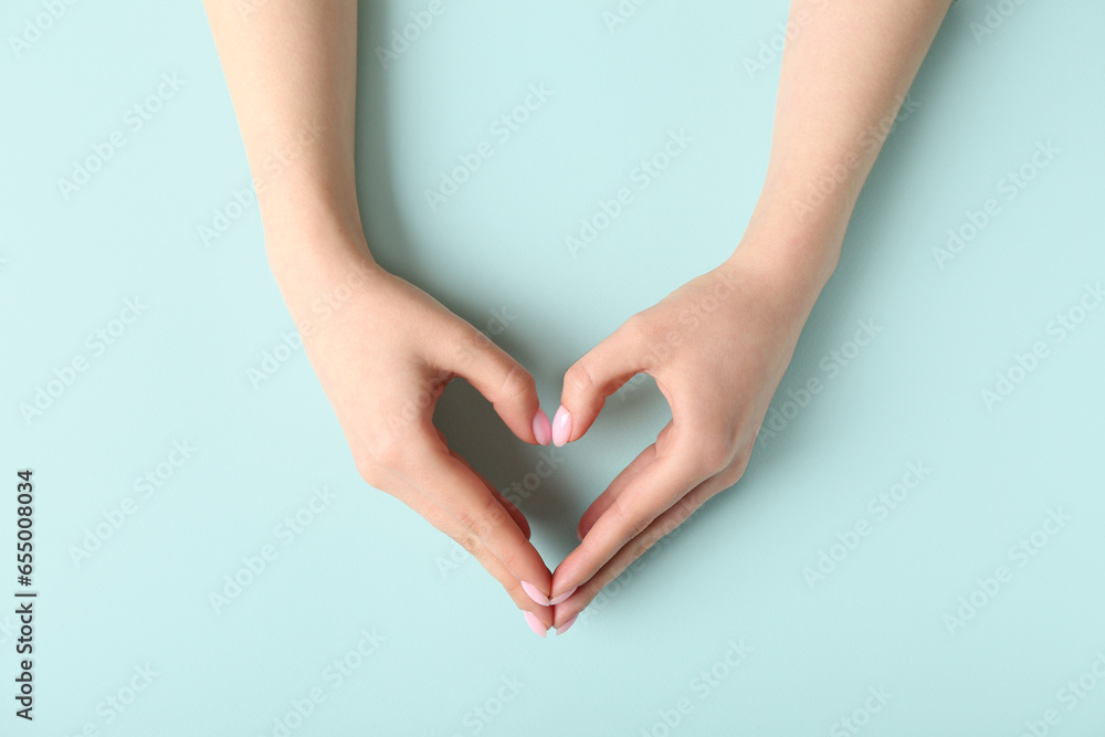 Woman making heart with her hands on blue background