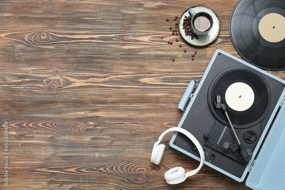 Record player with vinyl disks, headphones and cup of coffee on wooden background