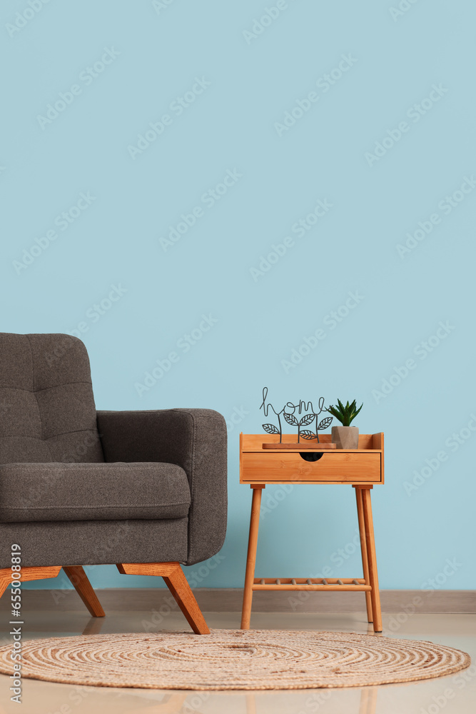 Interior of room with armchair and table near light blue wall