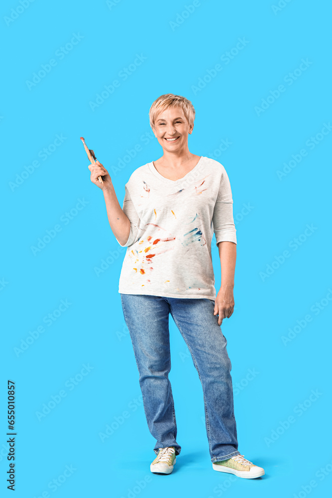 Mature female artist with tools on blue background