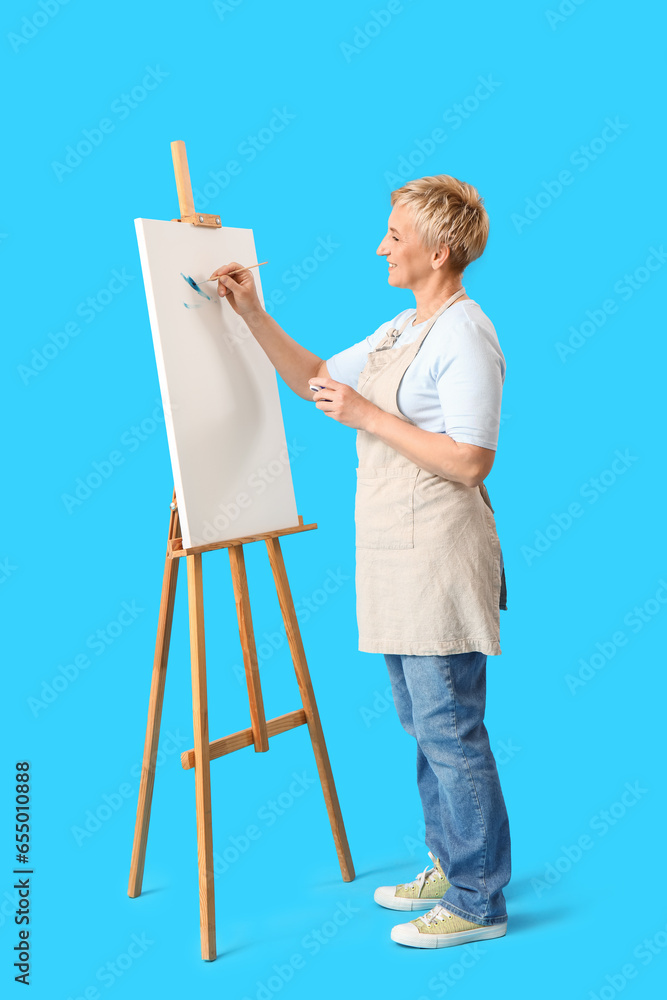 Mature female artist painting picture on blue background