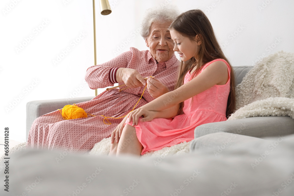 Little girl with her grandmother knitting at home