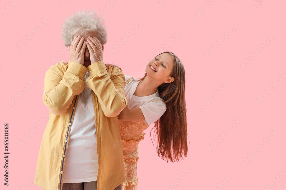 Little girl and her grandmother closing eyes on pink background