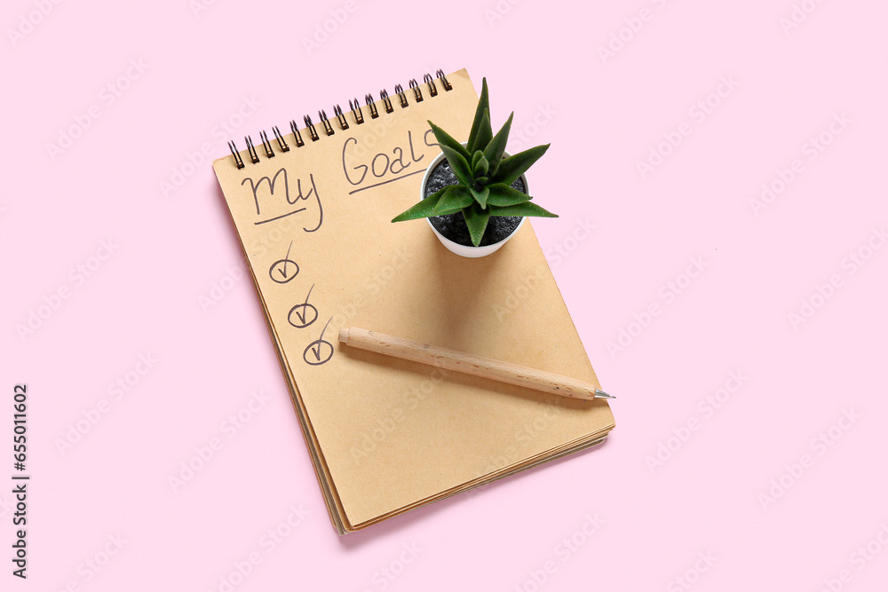 Notebook with empty to do list, pen and houseplant on pink background. New year goals