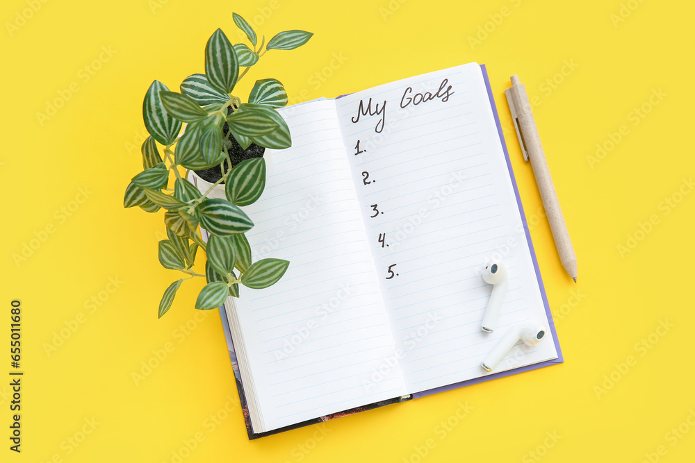 Notebook with empty to do list, pen and houseplant on yellow background. New year goals