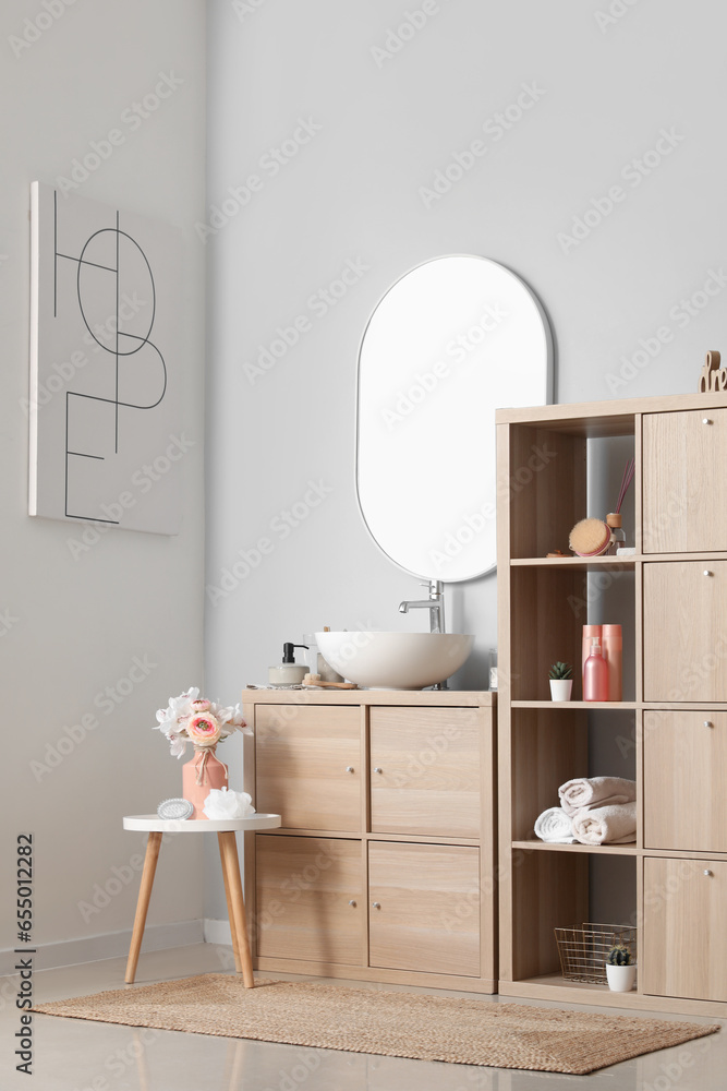 Interior of bathroom with sink bowl on wooden cabinet and shelving unit