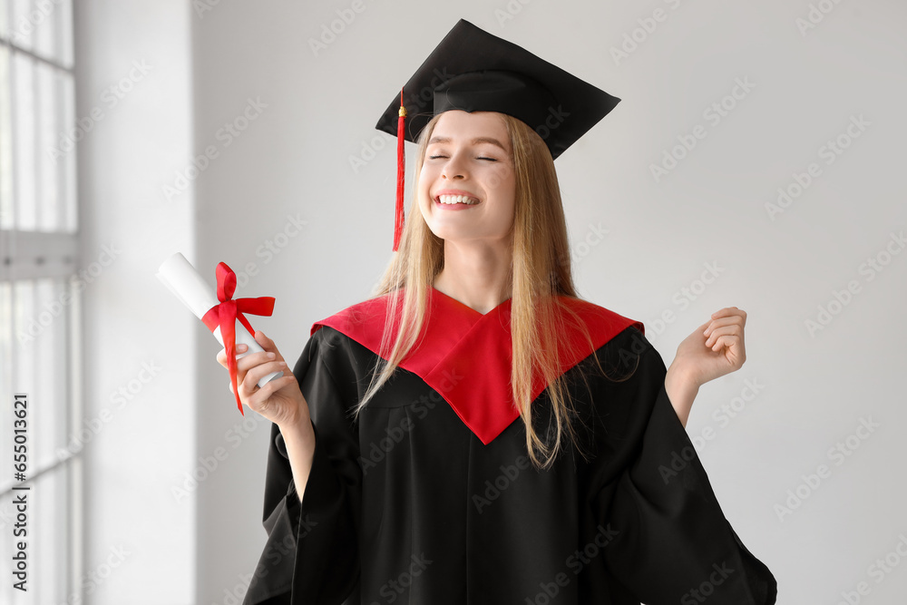 Female graduate student with diploma near window in room