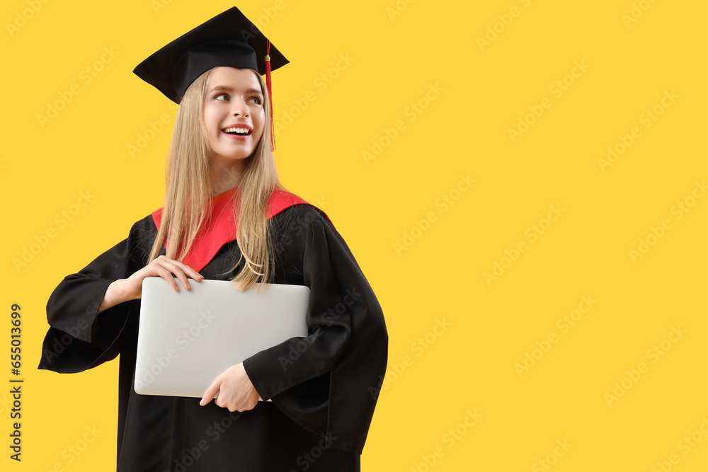 Female graduate student with laptop on yellow background