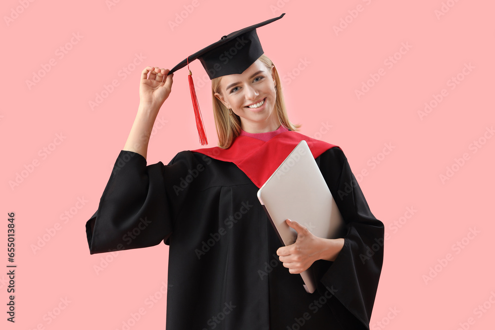 Female graduate student with laptop on pink background