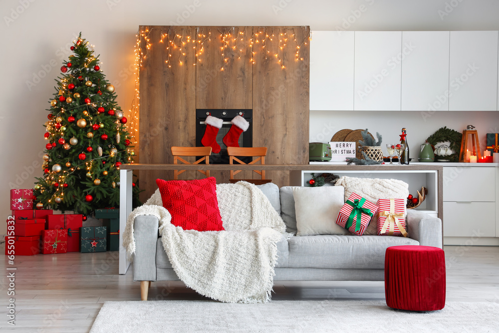 Interior of light open space kitchen with grey sofa and Christmas decor