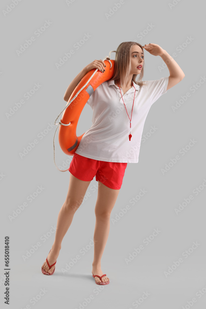 Female lifeguard with ring buoy on light background