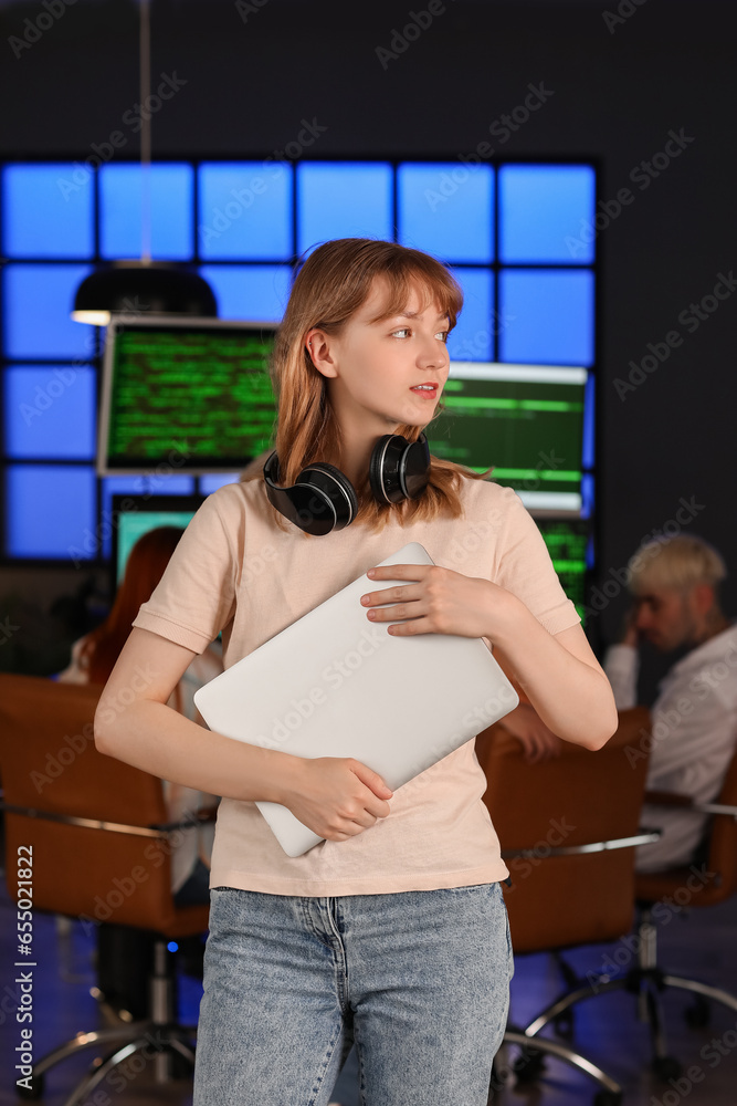 Female programmer with laptop in office at night