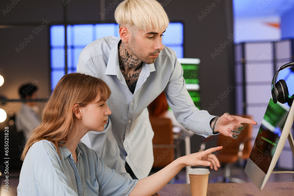 Young programmers working with computer in office at night