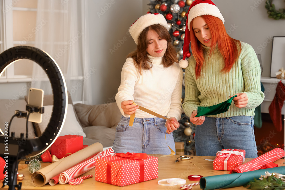 Young women with Christmas ribbons recording video at home