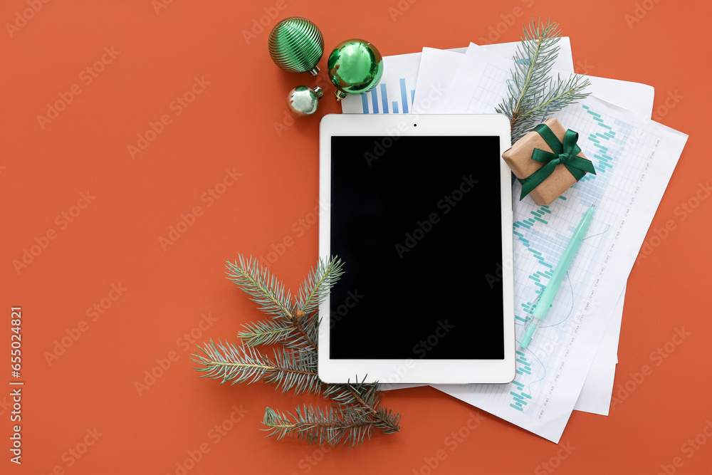 Tablet computer with diagrams and Christmas decor on brown background