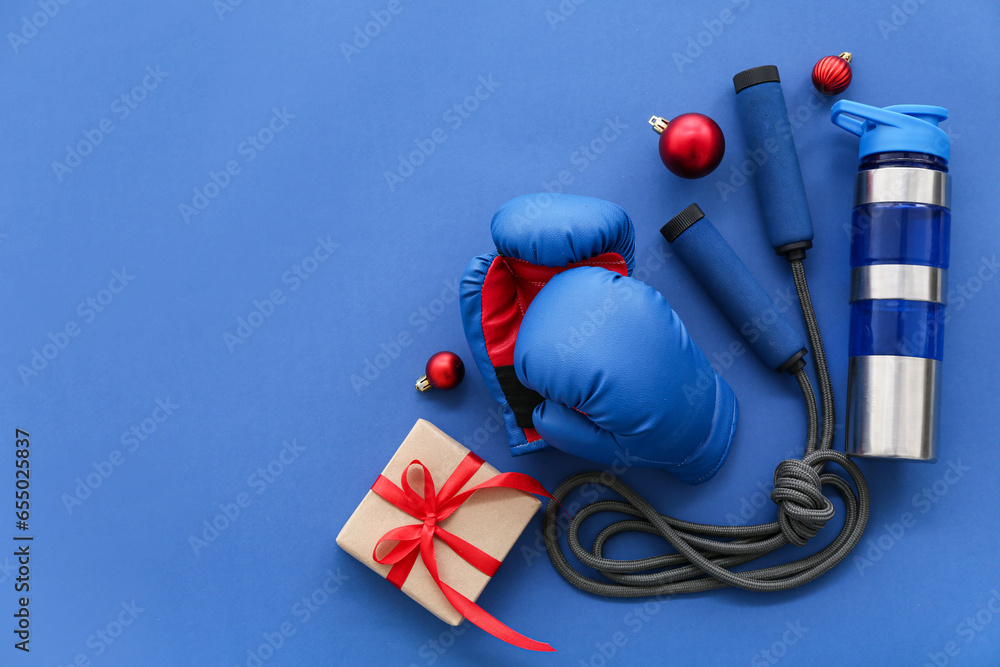 Sports equipment with Christmas balls and gift on blue background