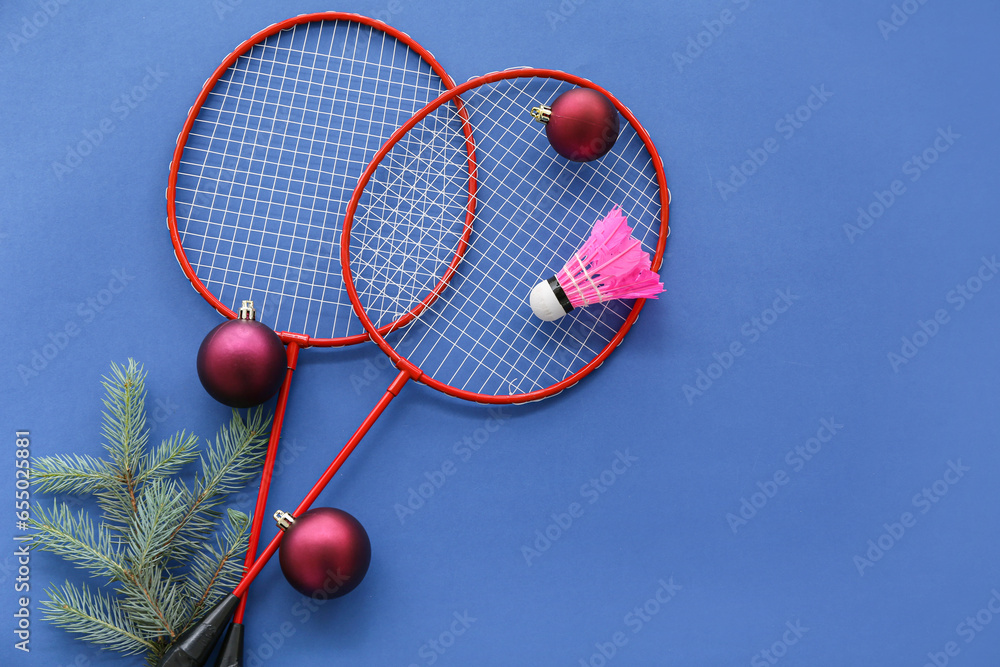 Badminton rackets with shuttlecock and Christmas decor on blue background