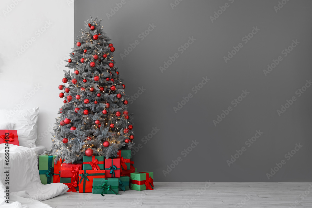 Gift boxes under Christmas tree near grey wall