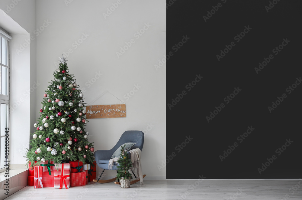 Gift boxes under Christmas tree and white armchair in festive room