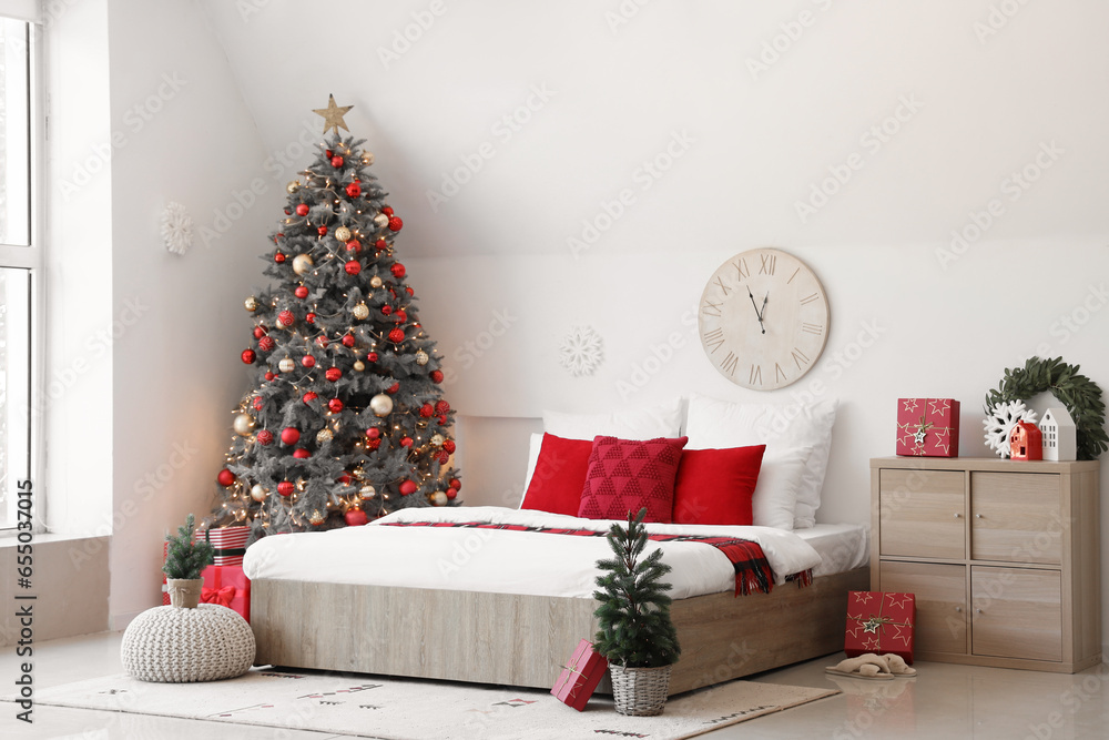 Interior of festive bedroom with comfortable bed and Christmas tree