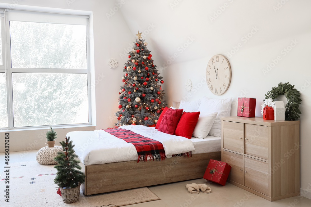 Interior of festive bedroom with comfortable bed and Christmas tree