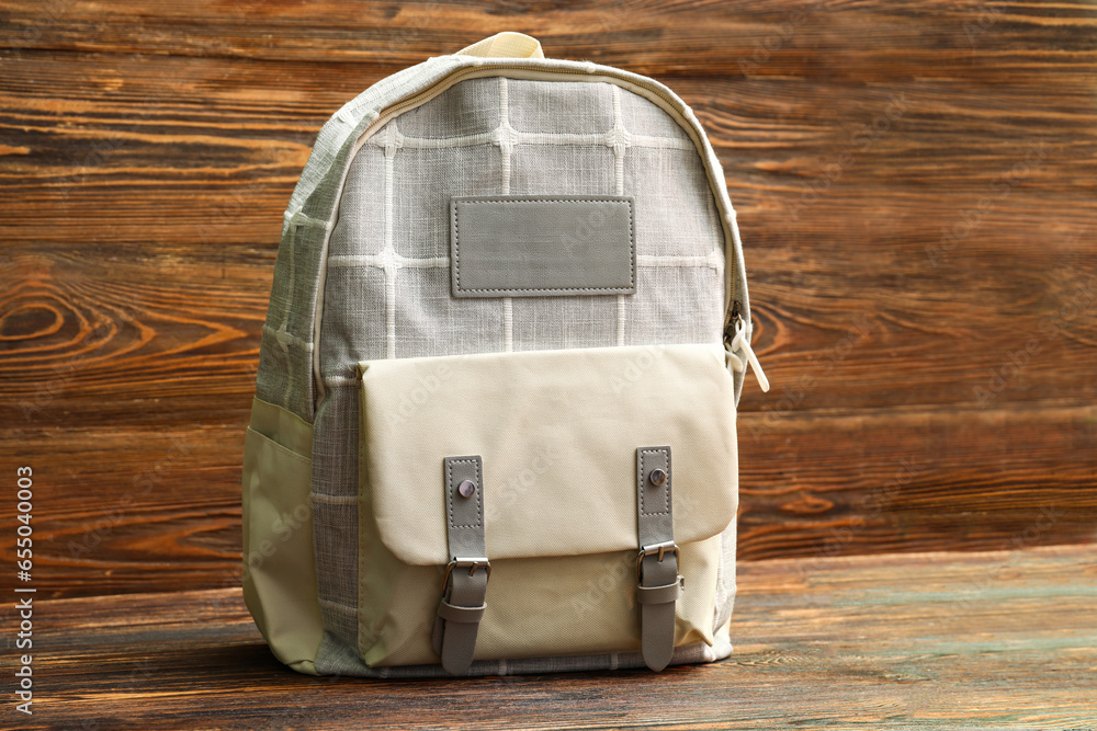 Grey school backpack on wooden background