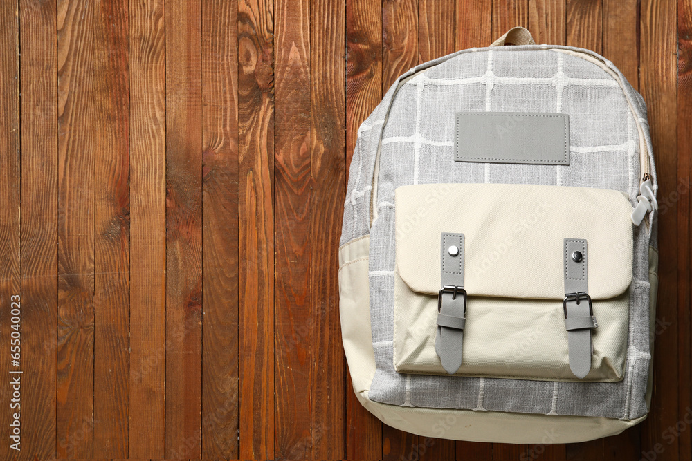 Grey school backpack on wooden background