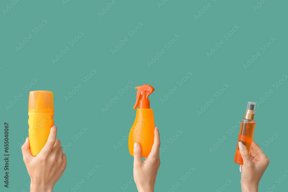 Female hands with bottles of sunscreen cream on green background