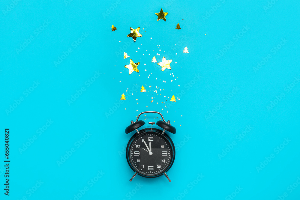 Alarm clock and confetti on blue background