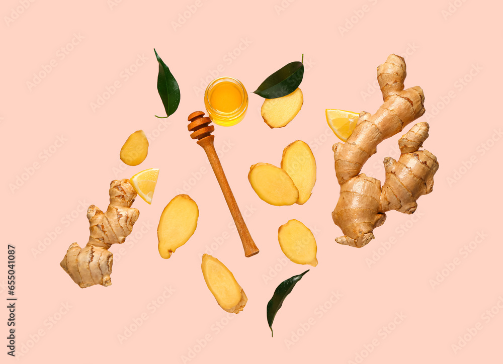 Flying slices of fresh ginger root and jar with honey on pink background