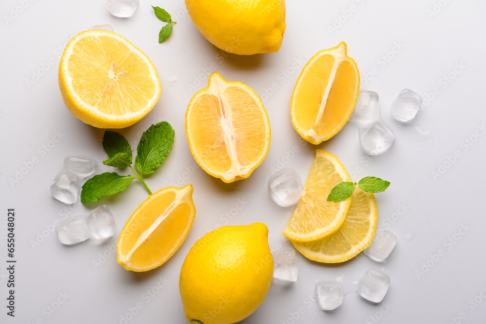 Fresh lemons with ice cubes on light background