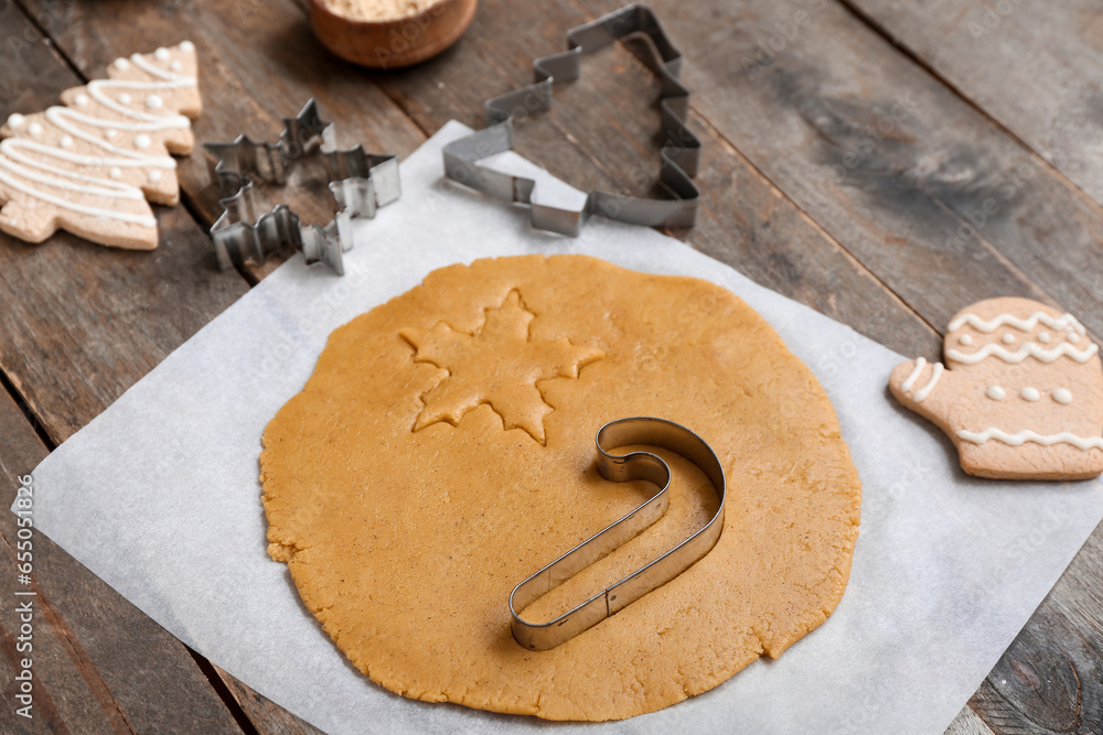 Raw dough for preparing tasty Christmas cookies and cutters on wooden background