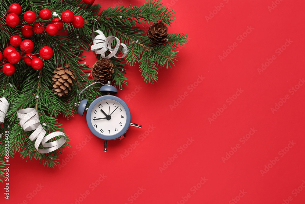 Alarm clock and Christmas tree branches with rowan on red background