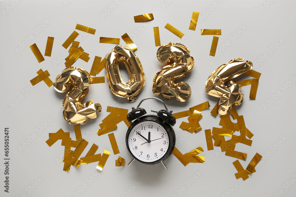 Figure 2024 made of foil balloons with alarm clock and confetti on white background