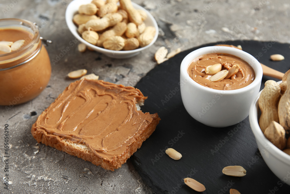 Toast with peanut butter and nuts on grey background